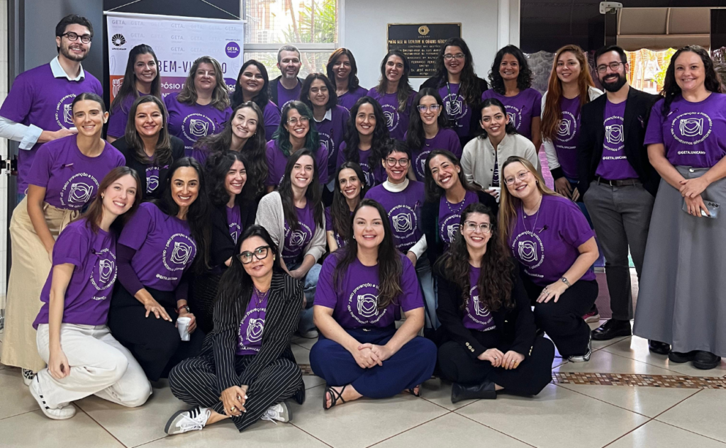 Ambulatório de Transtornos Alimentares da Unicamp celebra 20 anos com primeiro simpósio na área. Na imagem, a equipe do ambulatório posa para foto, vestindo uma camiseta na cor roxa, com a identidade visual do evento.