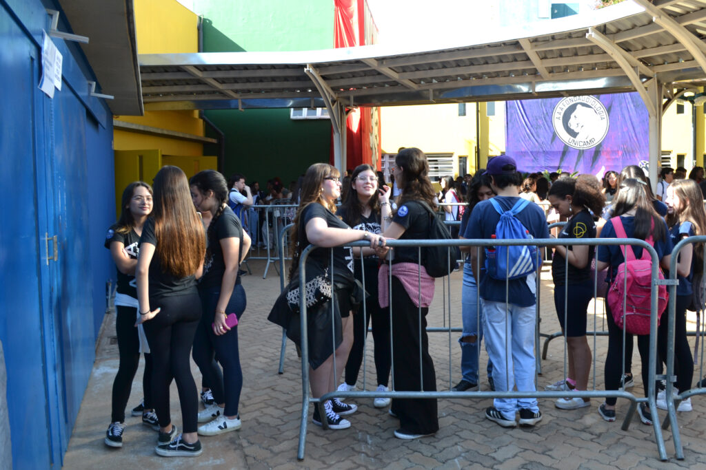 Estudantes e visitantes circulam em área externa do campus, ao lado de tendas brancas montadas para atividades do evento.