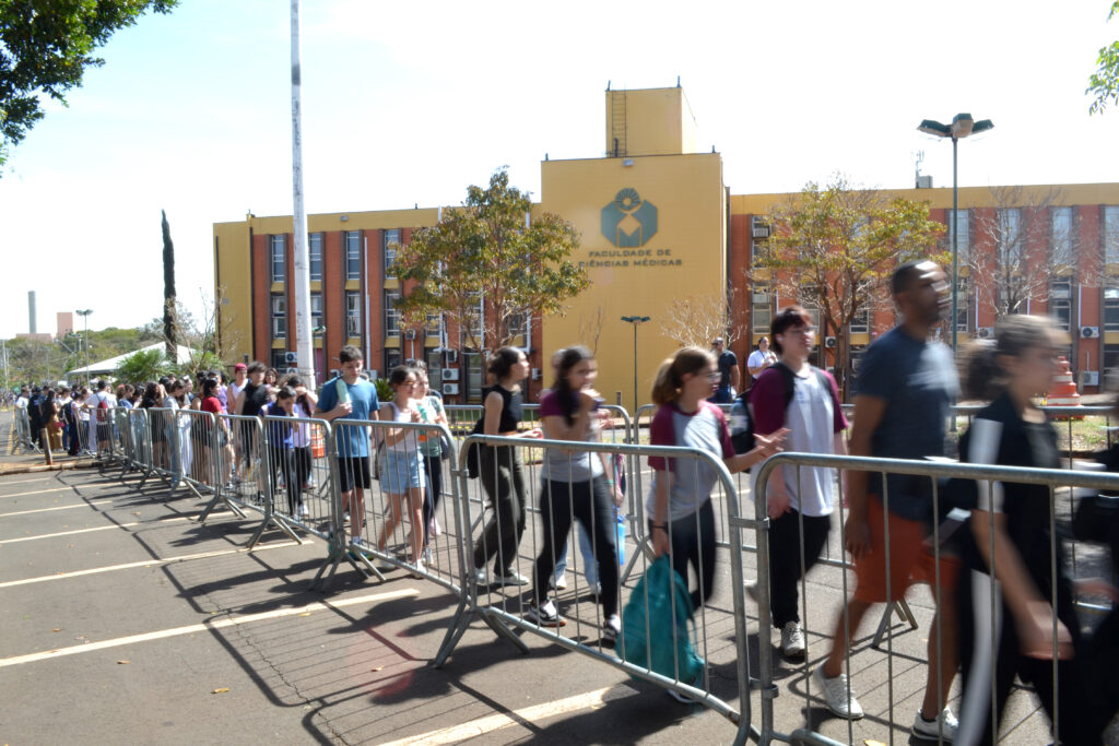 Longa fila de visitantes organizada por grades em frente ao prédio da Faculdade de Ciências Médicas da Unicamp.