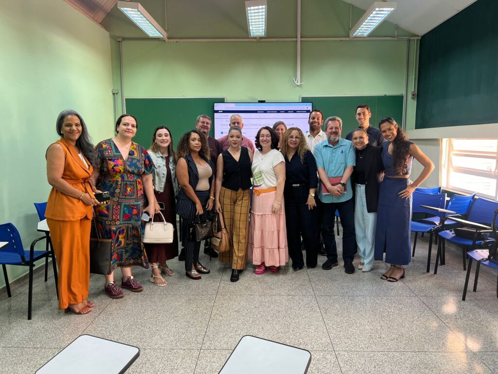 Grupo de profissionais reunidos em sala de aula, sentados em círculo, conversando e trocando experiências.