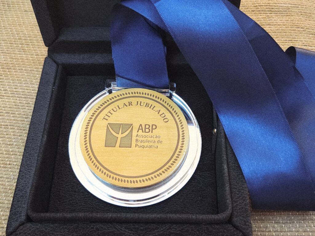Medalha dourada com fita azul, gravada com os dizeres “Titular Jubilado” e o logotipo da Associação Brasileira de Psiquiatria, disposta em caixa preta de veludo.