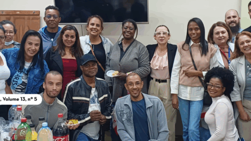 “Grupo numeroso de pessoas reunidas em uma sala, posando para a foto. Estão em pé e sentadas, sorrindo para a câmera. À frente, há uma mesa com garrafas de bebidas e alguns alimentos. No canto esquerdo da imagem, sobreposto, aparece o logotipo ‘Boletim da FCM’ acompanhado do texto ‘Saúde da População Negra – Ano 2025, Volume 13, nº 5’. A cena transmite clima de confraternização e integração.”