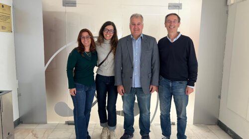 Quatro pessoas posam sorrindo em frente à entrada do Centro de Simulação, em um corredor iluminado. Duas mulheres estão à esquerda e dois homens à direita.